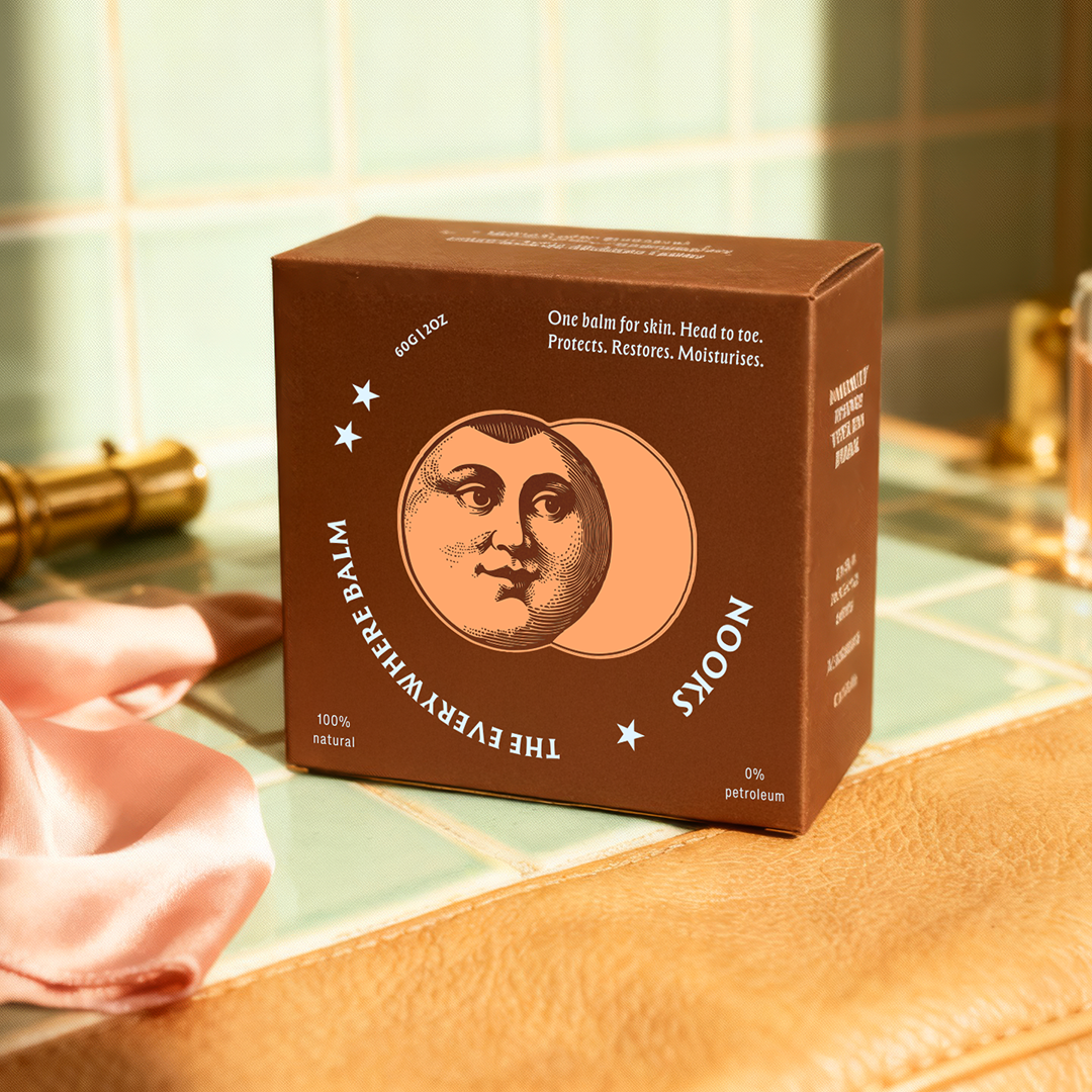 Brown box with moon design on a tiled surface with a pink cloth and bottles.