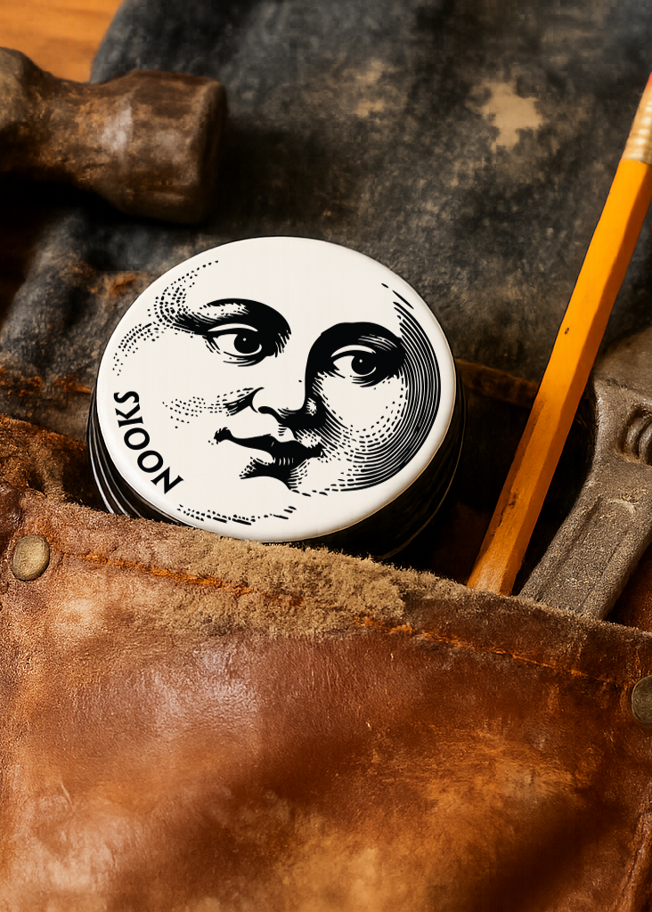 Vintage tools including a hammer, wrench, and pencil on a worn leather surface with a tin featuring a moon face design.