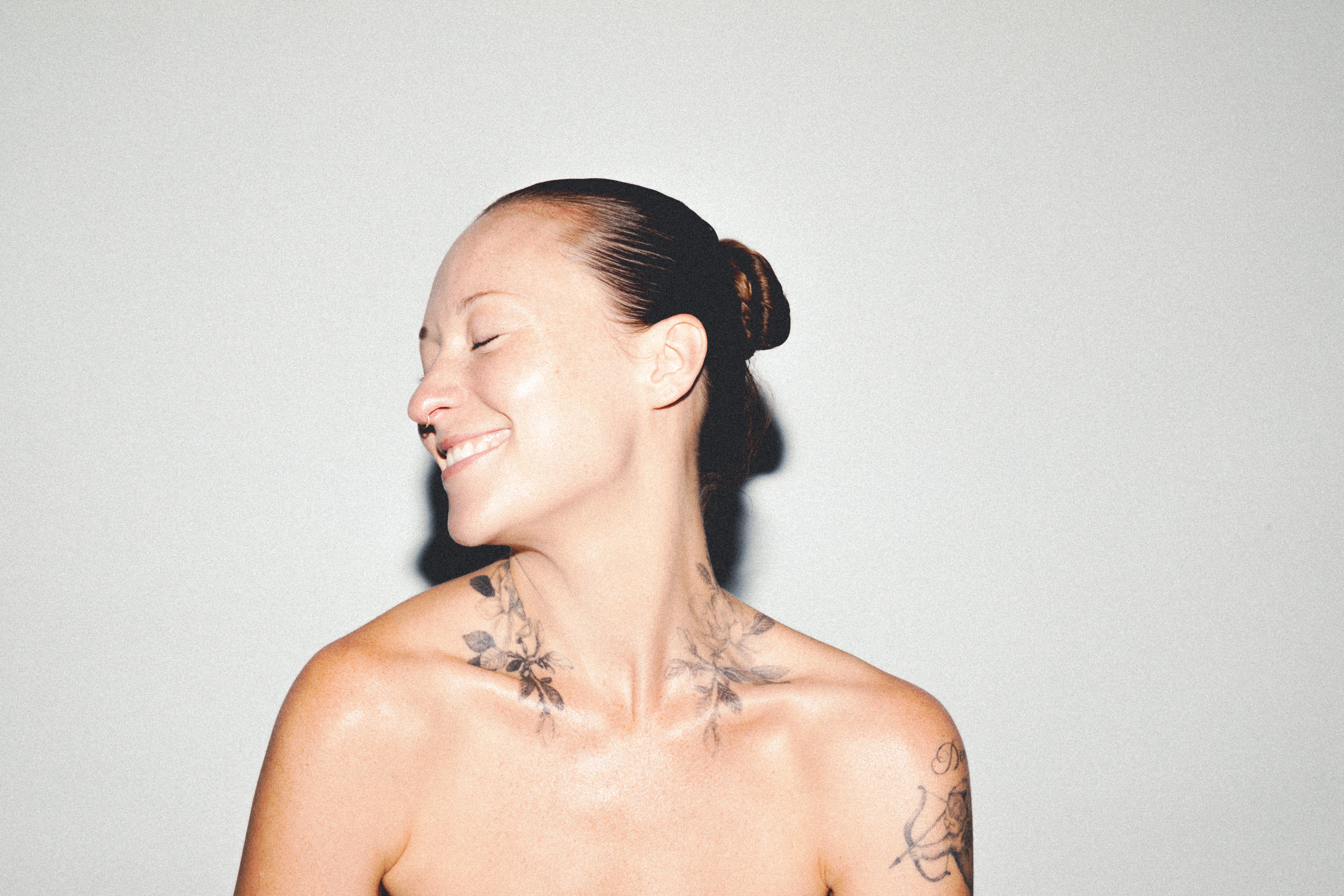 Model with eyes closed and bare shoulders, flash-lit skin